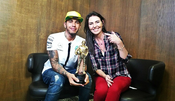 Hamilton sorri com trofeu que ganhou da família de Senna ao lado de Glenda Kozlowski (Foto: Priscila Carvalho)