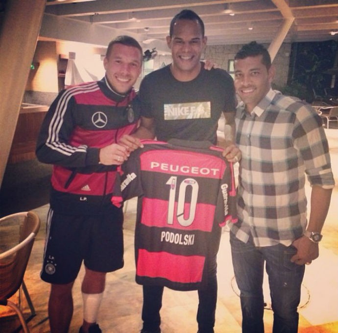 Podolski com André Santos mostra camisa do Flamengo (Foto: Reprodução)