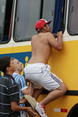 Torcedor tenta escalar ônibus do Grêmio (Foto: Diego Guichard)