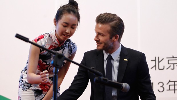 David Beckham ao lado de uma estudante aprendendo um instrumento chinês tradicional (Foto: Agência Reuters)