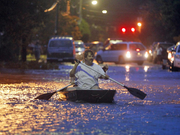 Dois homens usam botem para circular por via alagada na Carolina do Norte durante passagem do furacão Irene pelo estado (Foto: John Bazemore/AP)