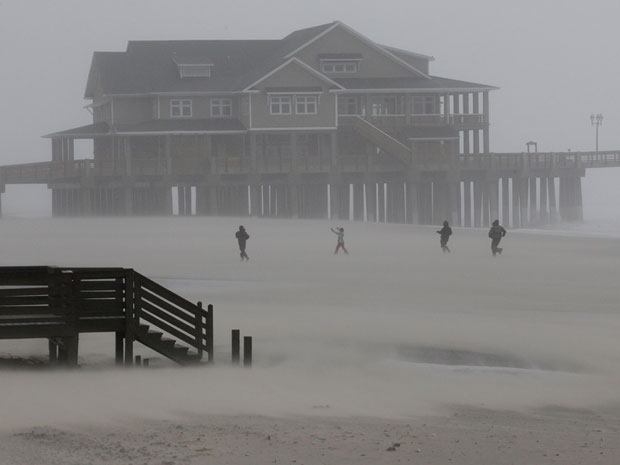 Pessoas caminham por Nags Head, no litoral da Carolina do Norte, mesmo com os efeitos do furacão Irene (Foto: AP)